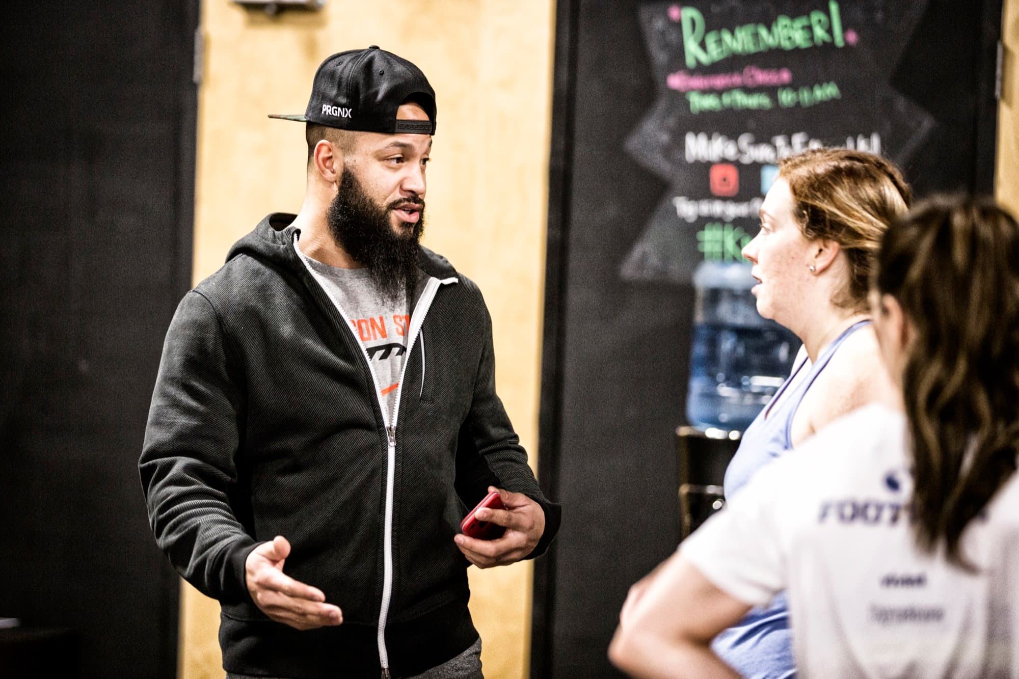 Coach Matt Byrd in a black hoodie coaching an athlete beside the whiteboard