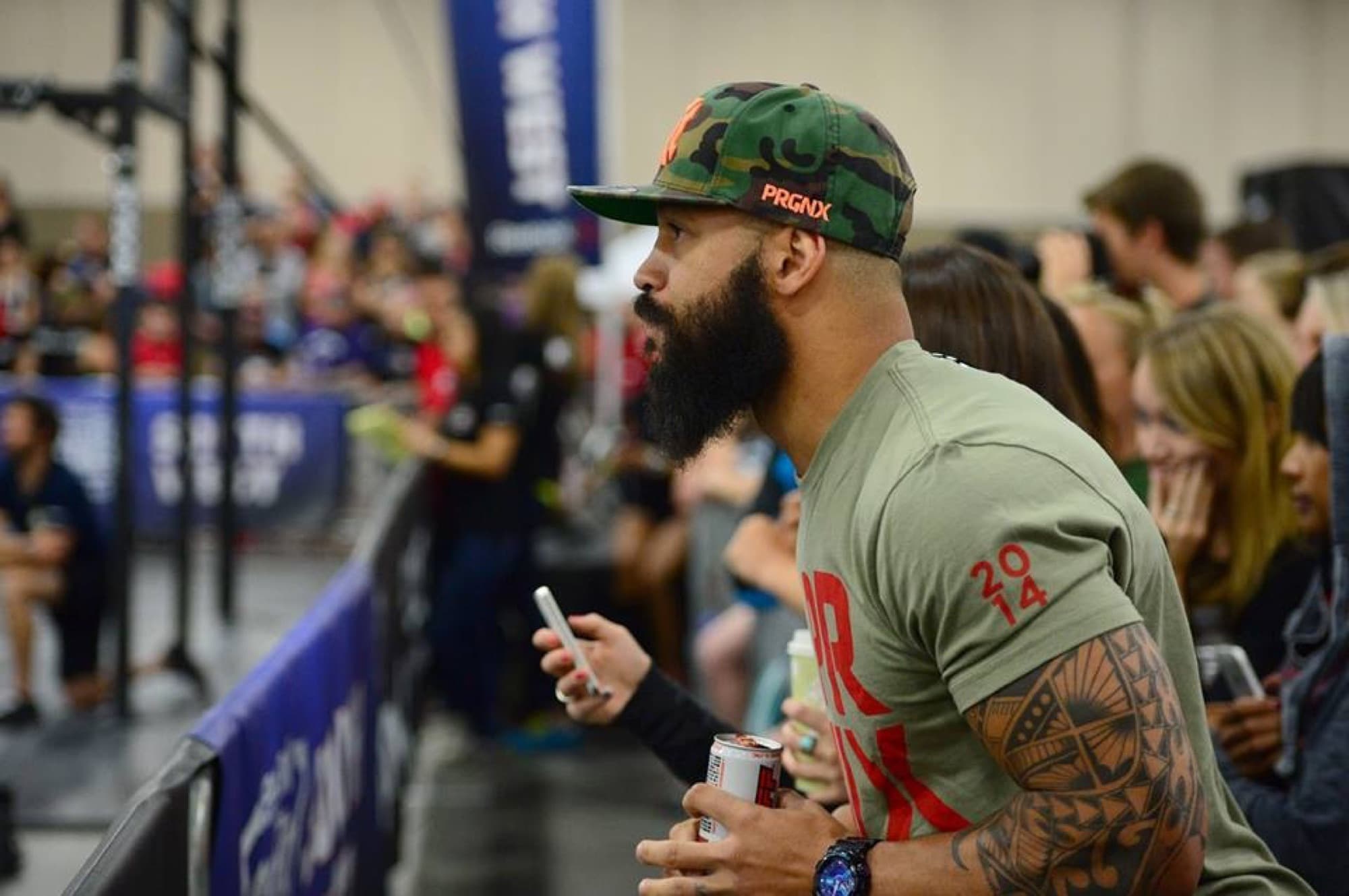 Coach Matt Byrd in a camo hat watching the floor at a CrossFit competition